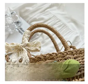 Close-up of handmade straw tote featuring lace bow and green floral charm detail