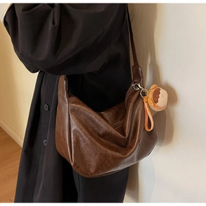 Détail du sac hobo en cuir marron foncé avec pendentif de poupée mignon