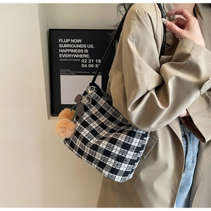 Détail d'un sac cabas en tweed noir et blanc avec un charmant pompon en peluche