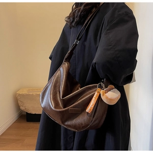 Détail du sac vintage marron en similicuir avec finition brillante et charme en peluche