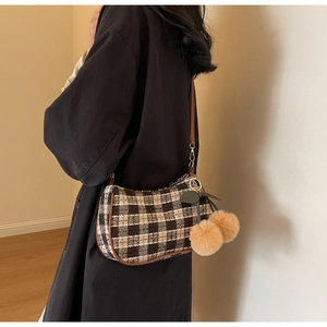 Detail of checkered tweed shoulder bag with oversized cherry charm and leather piping
