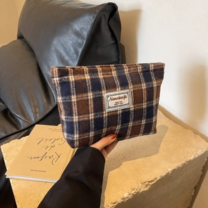 Macro detail of the vintage plaid wool fabric and durable metal zipper on the cosmetic bag
