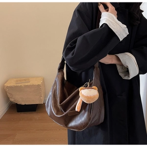 Vue détaillée du grand sac bandoulière marron foncé avec un joli pendentif peluche
