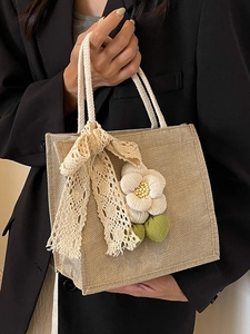 Linen tote bag with 3D white flower and lace bow shown in a model handheld pose