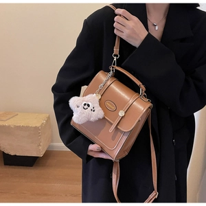Brown faux leather crossbody bag with star charm and metal logo on black suit