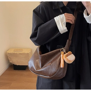 Détail du sac bandoulière rétro marron foncé avec pendentif en peluche et texture plissée
