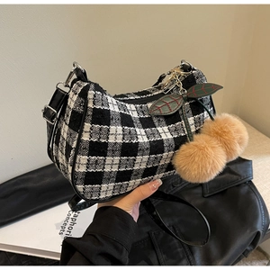 Detail of checkered hobo bag with a red cherry charm and black leather strap