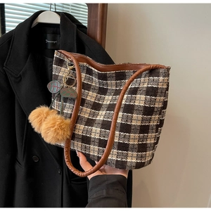 Gros plan du cabas en tweed à carreaux avec un joli pendentif cerise en peluche