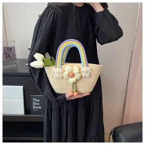 Detail of woven straw bag featuring rainbow handle, floral decor, and cherry charms