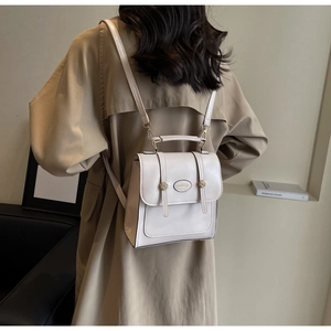 Detail of a vintage beige PU leather mini backpack with metal buckle and top handle