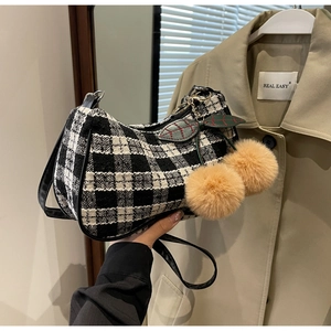 Detail of checkered hobo bag with plush cherry charm and sleek black leather trim