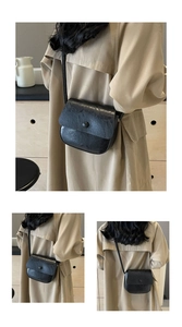 Detailed close-up of a black vintage textured flap bag with a circular buckle detail