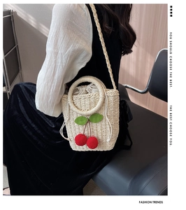 Detail of hand-woven straw bag with red pompom cherries and drawstring liner