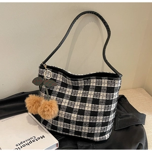 Détail du sac cabas en tweed noir et blanc avec breloque cerise et bandoulière en cuir
