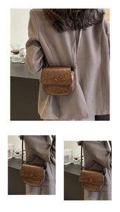 Detail of a dark brown saddle bag with retro wrinkled texture and round snap closure