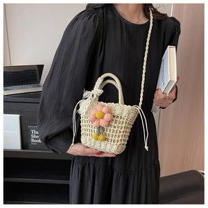 Detail of hand-woven straw bag with pink 3D flowers and lace bow on a black dress
