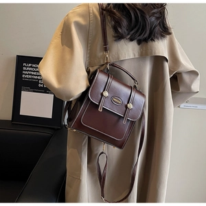 Close-up of brown vintage faux leather backpack with metallic buckle and contrast stitching
