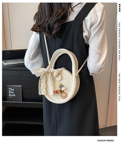 Détail du sac rond en paille crème avec nœuds en dentelle et décorations florales