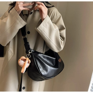Détail du sac croissant noir plissé avec logo marron et breloque en peluche pour femme