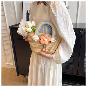 Close-up of woven straw handbag with rainbow handles and orange 3D flower detail
