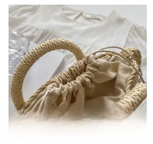 Detail of beige straw handbag featuring a linen drawstring closure and woven handle