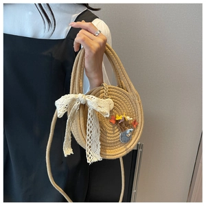 Détail du sac rond en paille avec nœud en dentelle blanche et écusson mouton brodé