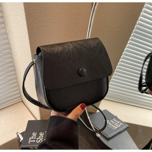 Detail of black faux leather saddle bag with vintage crinkled texture and magnetic closure