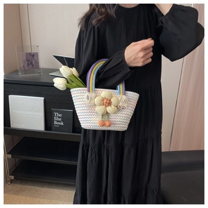 Close-up of woven straw bag with floral decor, cherry pendant and colorful handles
