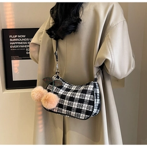 Detail of houndstooth shoulder bag featuring cute cherry plush charm and black leather trim