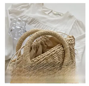 Detail of woven straw handbag with drawstring lining and decorative green leaf patch