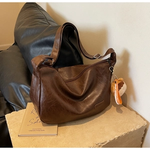 Détail du sac hobo marron foncé avec logo embossé et charmant pendentif en peluche