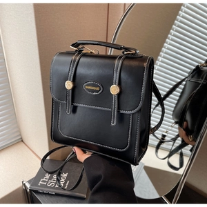 Detail of black vintage backpack featuring contrast white stitching and gold buckle