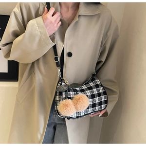 Detail of black and white checkered tweed shoulder bag with a cute cherry plush charm