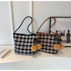 Détail de sacs fourre-tout à carreaux noirs et marrons avec breloques cerise en peluche