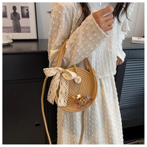 Détail du sac rond en paille avec nœud en dentelle, fleurs et texture tressée