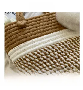 Detail der handgeflochtenen Stroh-Eimertasche mit weißem flauschigem Bommel und zweifarbigem Design