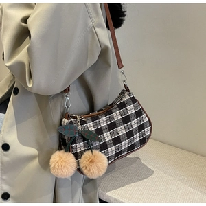 Detail of retro houndstooth shoulder bag with brown strap and plush cherry charm