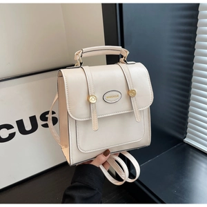 Close-up of cream PU leather backpack featuring gold circular buckles and a top handle