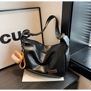 Gros plan d'un sac noir avec étiquette FASHION et pendentif en peluche marron