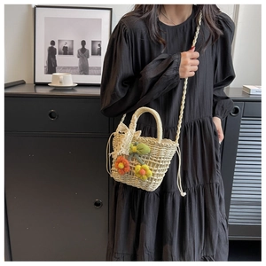 Detail of handmade straw bag with orange floral embroidery and lace bow on strap