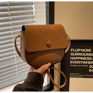 Detail shot of a brown vintage saddle bag featuring textured faux leather and flap magnetic buckle