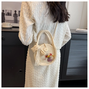 Détail du sac en paille avec nœud en dentelle et appliques florales dans un décor lifestyle