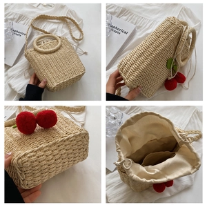 Macro view of woven straw bag with cherry pendants and drawstring fabric lining