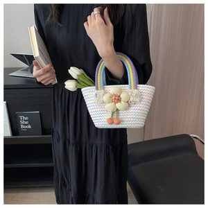 Detail of woven tote bag featuring rainbow handles, floral accents and cherry charm