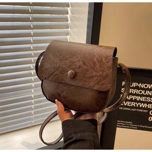 Detailed macro view of dark brown retro shoulder bag with cracked faux leather texture