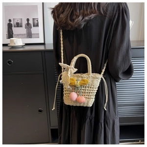 Straw woven mini bucket bag with pink cherry charms and lace bow on a model