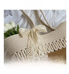 Détail du sac de plage bicolore avec un nœud en dentelle crème et une texture tressée