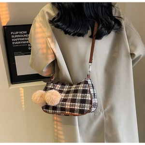 Detail of retro plaid hobo shoulder bag with a cute cherry plush pendant on a model