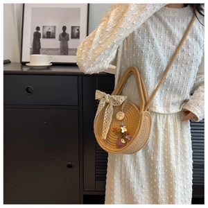 Détail du sac rond en paille avec nœud en dentelle et fleurs sur un mannequin en blanc