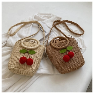 Close-up of woven straw handbag featuring 3D cherry pattern and drawstring lining